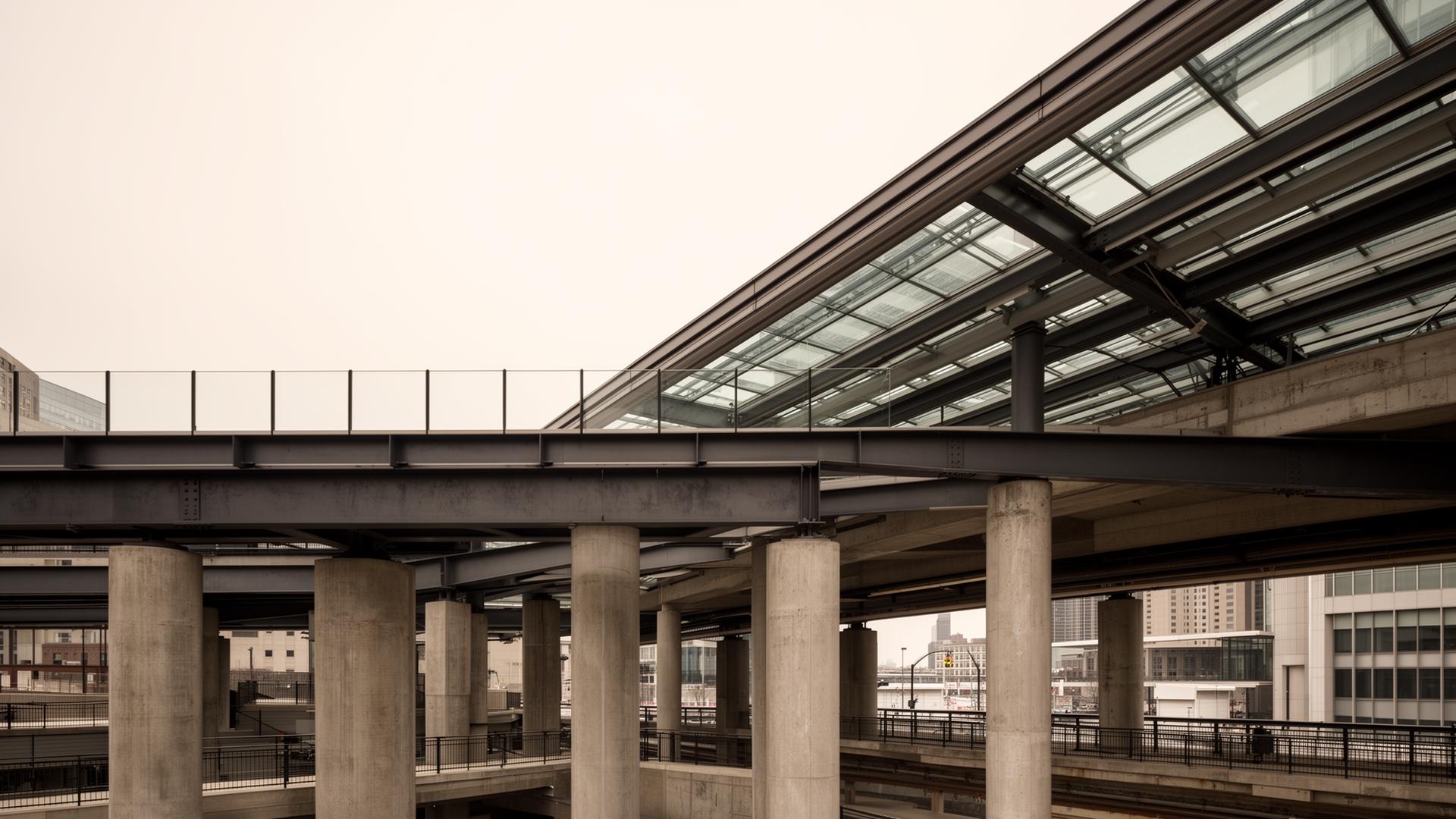 Elevated transit station with steel girders, glass canopy, and concrete piers in a Chicago urban setting
